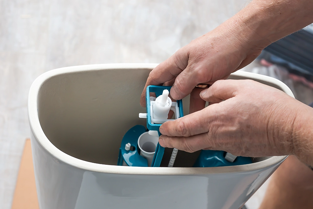 Hands aligning the flushing mechanism in the back of the toilet